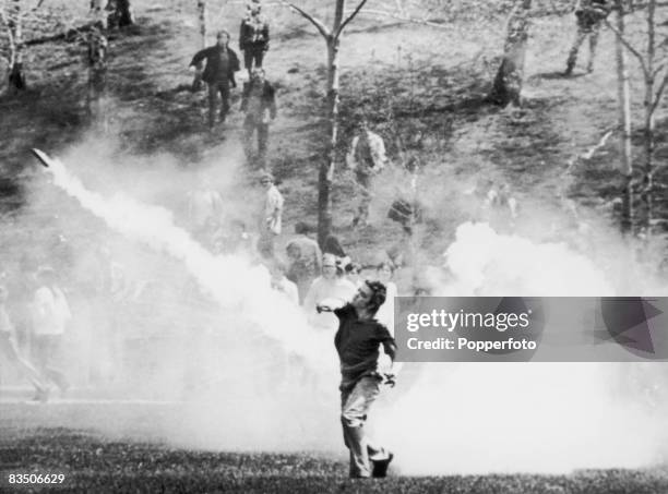 Student throws a tear gas canister back at National Guardsmen during a demonstration against the American invasion of Cambodia, at Kent State...