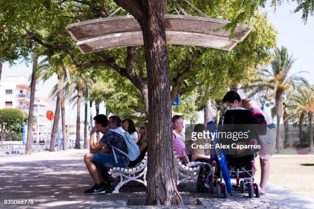 Tourists seat on a bench next to the spot where five terrorists were shot by police on August 18, 2017 in Cambrils, Spain. Fourteen people were...