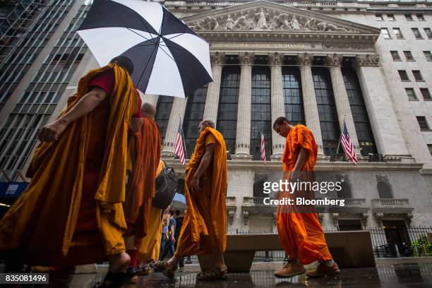 Pedestrians walk past the New York Stock Exchange in New York, U.S., on Friday, Aug. 18, 2017. Stocks were mixed and the S&P 500 Index turned higher...