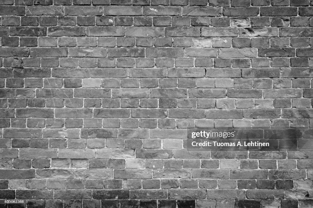 Old and aged brick wall texture background with vignetting in black and white.