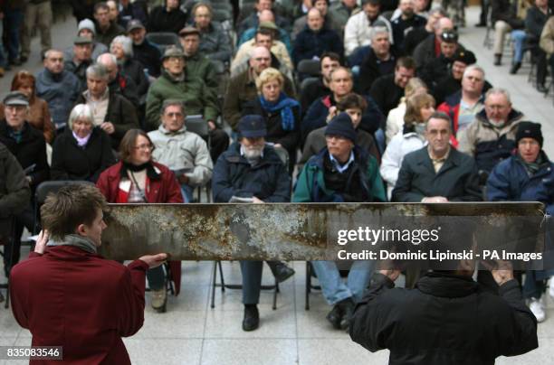 Bidders look at a metal train nameplate at a charity auction of over one hundred train nameplates, at Waterloo Station, London.