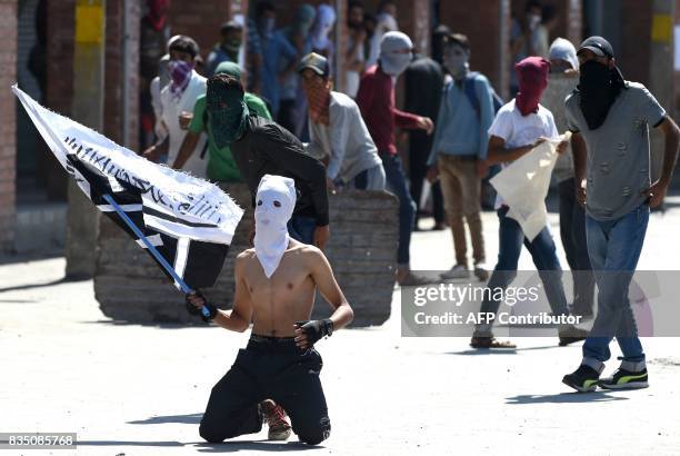 Masked Kashmiri protestor waves a flag as others throw stones towards Indian government forces during clashes after Friday congregational prayers...