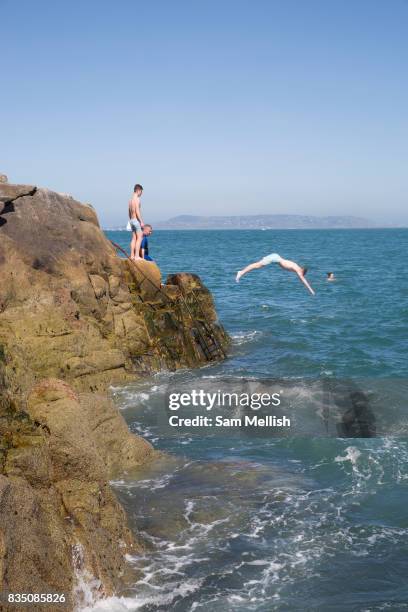 Young people rock diving into Dublin Bay at Sandycove on 08th April 2017 in County Dublin, Republic of Ireland. Sandycove is a popular seaside resort...