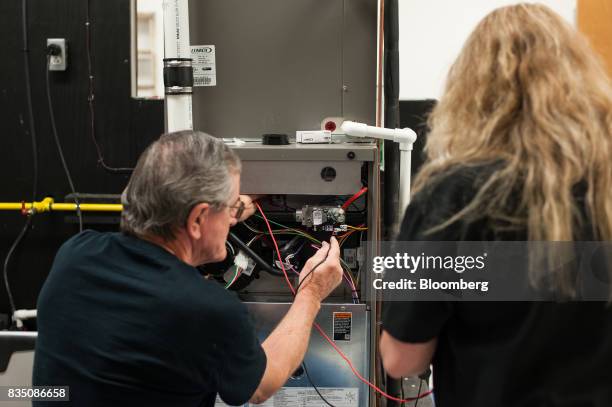 Gene Everly, left, of Greensboro, Pennsylvania, demonstrates how to test a furnace in a training classroom at the Penn Commercial Business/Technical...