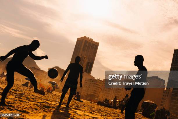 menschen, die fußball spielen, am strand der copacabana, rio de janeiro - famous footballers silhouette stock-fotos und bilder