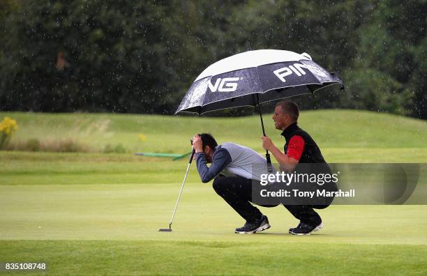 Barry Forster of North Wilts Golf Club and Dan Carter of Upavon Golf Club line up a putt under an umbrella in the rain during the Golfbreaks.com PGA...