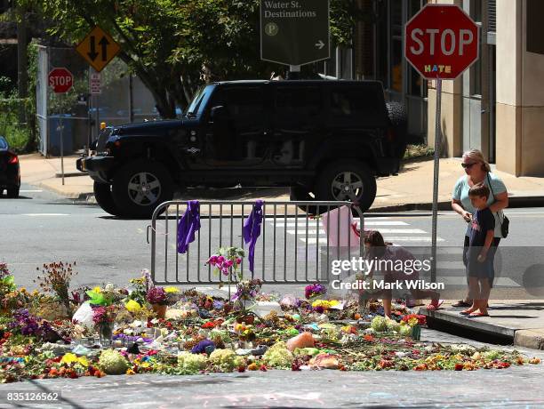 Seven year-old Lily Holtz places flowers on the street where Heather Heyer was killed and 19 others injured when a car slammed into a crowd of people...