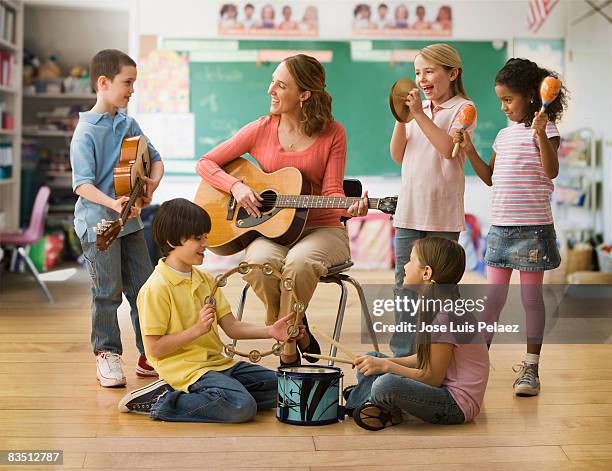 teacher teaching music lesson to children - musikalische begleitung stock-fotos und bilder