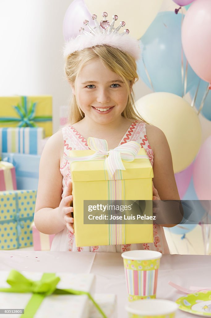 Young girl with tiara holding up birthday present