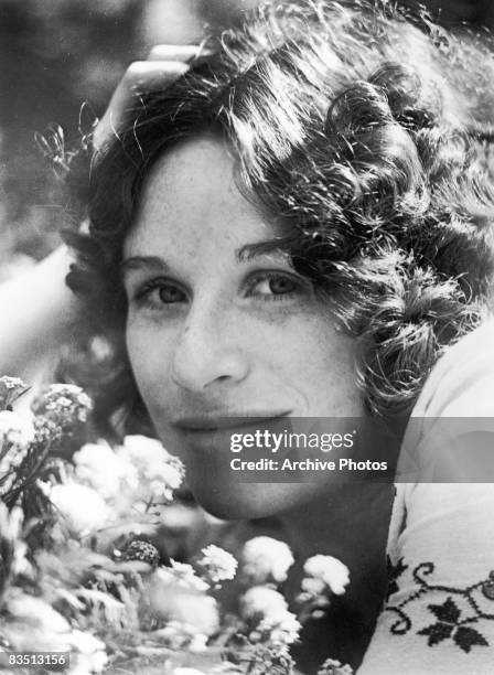 American singer and songwriter Carole King posing with flowers, circa 1975.