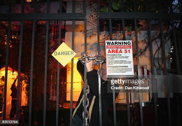 Man secures a chain on the gates as Jonathan Ross hosts a Halloween party at his home on October 31, 2008 in London, England. An enquiry was held...