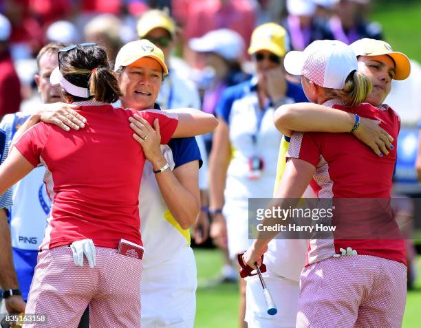 Catriona Matthew of Team Europe hugs Gerina Piller of the United States while Karine Icher hugs Stacy Lewis after winning one up on the 18th green...