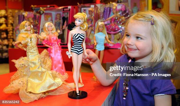 Lyla Mulcahy with a copy of the original 1959 Barbie doll in a zebra swimsuit, with other Barbies from the past five decades, at Hamleys toy store in...