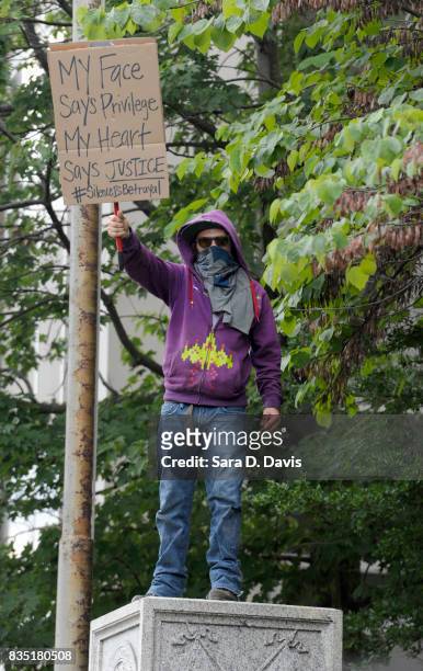 Demonstrator stands on the pedestal of where a Confederate soldier statue once stood before it was torn down by citizens on August 18, 2017 in...