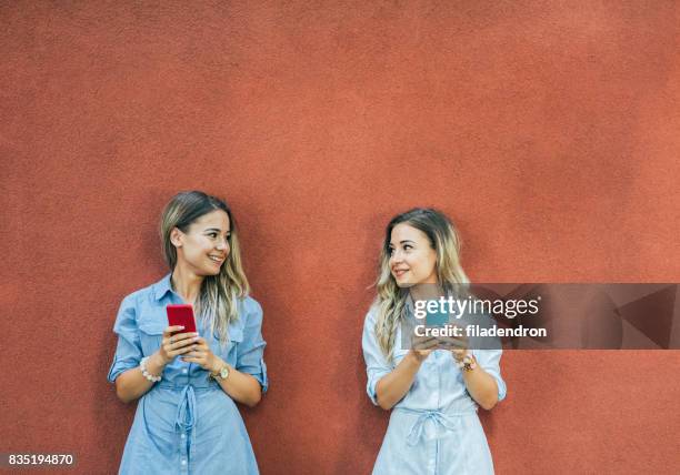 twins texting in de stad - identical twins stockfoto's en -beelden