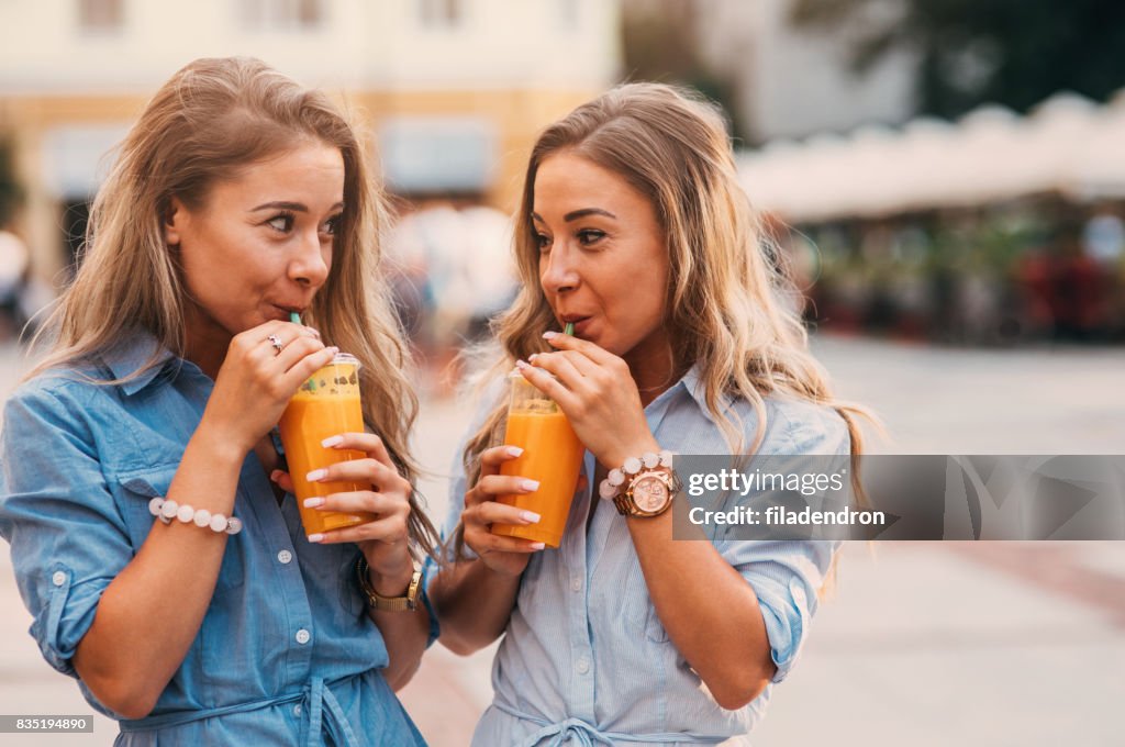 Twins drinking juice outdoors