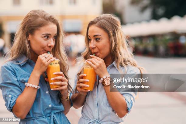 twins drinking juice outdoors - matching outfits stock pictures, royalty-free photos & images