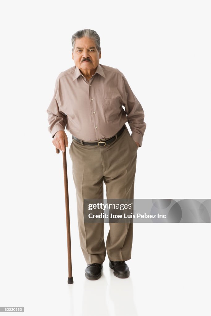 Senior Hispanic man walking with cane