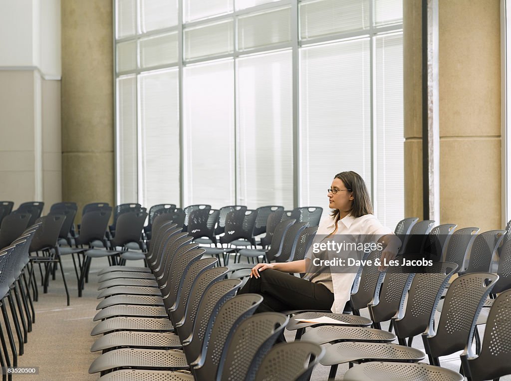 Hispanic businesswoman waiting in empty conference room