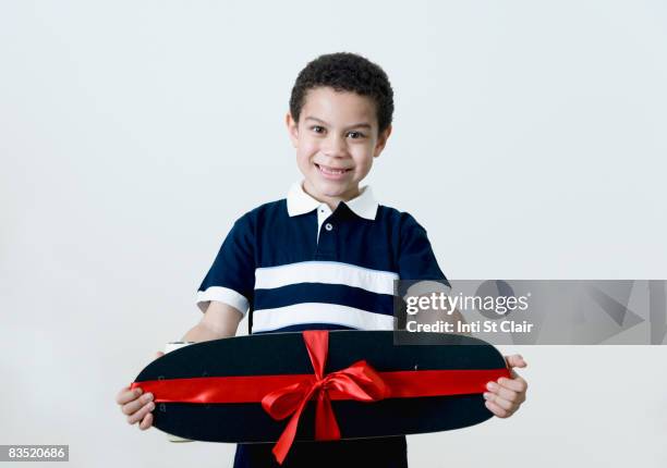 mixed race boy holding skateboard - boy holding picture cut out stock-fotos und bilder