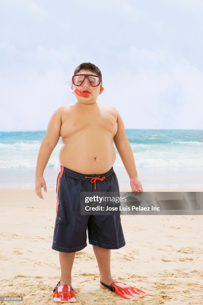 Hispanic boy standing at beach in snorkel gear
