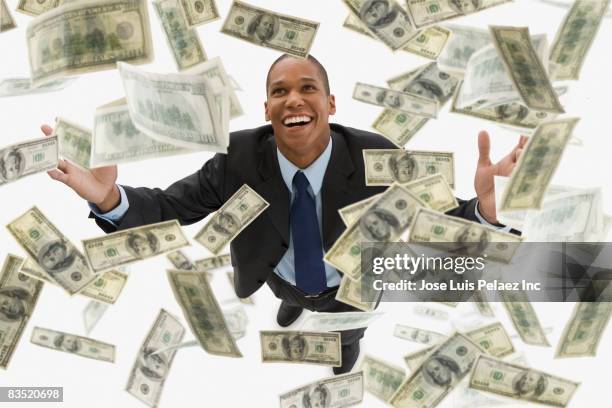 mixed race businessman catching falling 100 dollar bills - mixed race man standing studio stockfoto's en -beelden