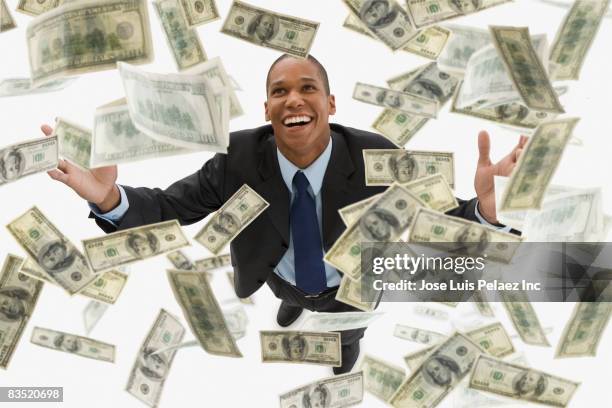 mixed race businessman catching falling 100 dollar bills - pennies from heaven stock pictures, royalty-free photos & images
