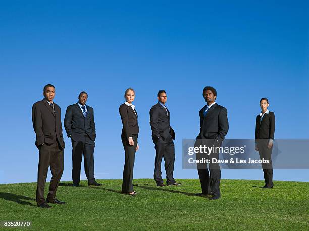 business people standing outdoors in grass - group of businesspeople standing low angle view stock pictures, royalty-free photos & images