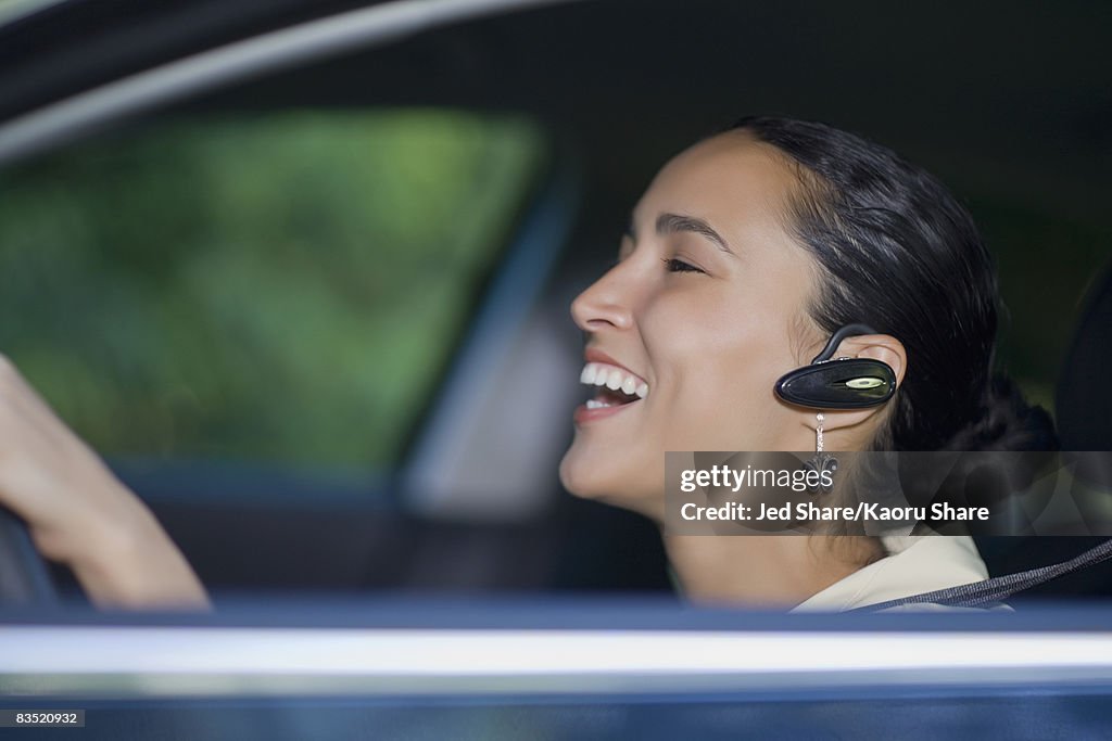 Hispanic woman driving with hands-free cell phone device