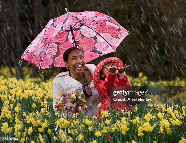 african mother and daughter playing in the rain - mother protecting from rain stock-fotos und bilder