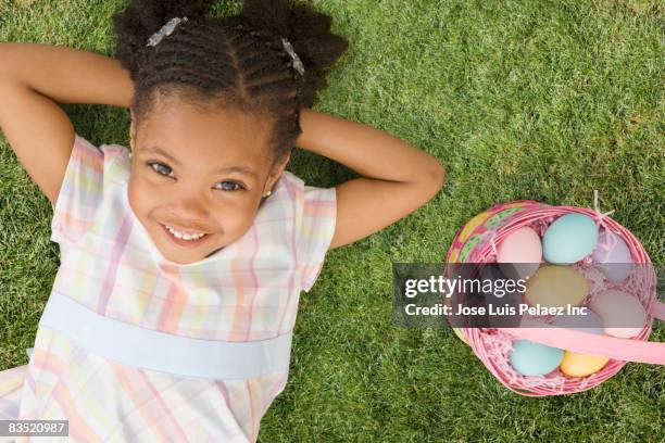 african girl laying next to easter basket - african easter stock pictures, royalty-free photos & images