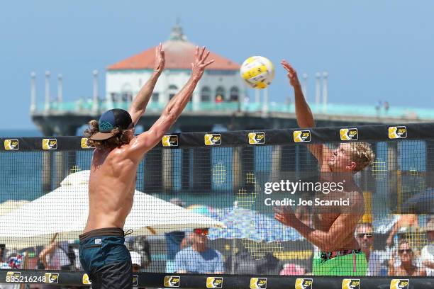 Avery Drost jumps to send the ball past a guarding Jeremy Casebeer during their round 2 match at the AVP Manhattan Beach Open - Day 2 on August 18,...