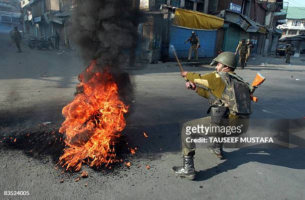 An Indian Central Reserve Police Force soldier tries to remove a burning tyre during a protest in the capital Srinagar on November 1, 2008 soon after...