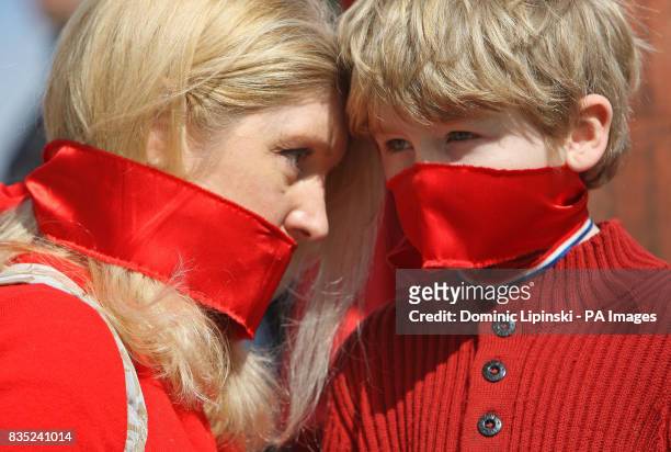 Birgit Cunningham and her son Jack Cunningham-Nuttall wear red gags over their mouths as they join in a protest at Piccadilly Circus, London, against...