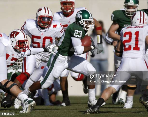 Javon Ringer of the Michigan State Spartans looks for running room during a second quarter run between O'Brien Schofield and Chris Maragos of the...