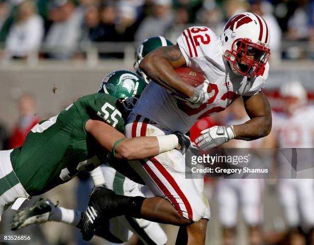 John Clay of the Wisconsin Badgers tries for extra yards during a third quarter run in front of Adam Decker of the Michigan State Spartans on...