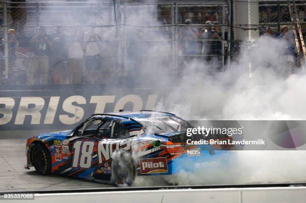 Kyle Busch, driver of the NOS Rowdy Toyota, celebrates with a burnout after winning the NASCAR XFINITY Series Food City 300 at Bristol Motor Speedway...