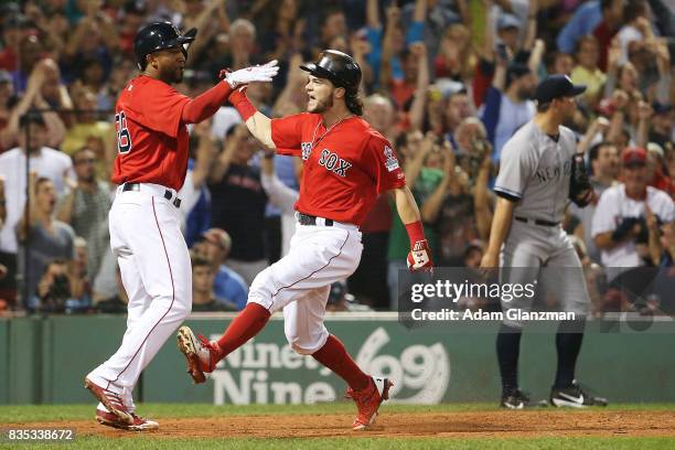 Tomy Kahnnle of the New York Yankees looks on as Andrew Benintendi and Eduardo Nunez of the Boston Red Sox high five after scoring to take the lead...