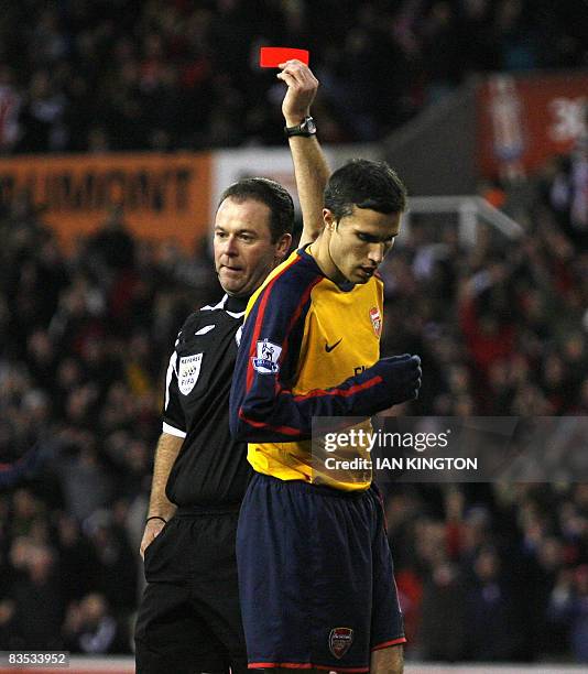 Referee Rob Styles gives Arsenal's Dutch player Robin van Persie a red card after a foul on the goalkeeper Stoke City's Danish player Thomas Sorensen...