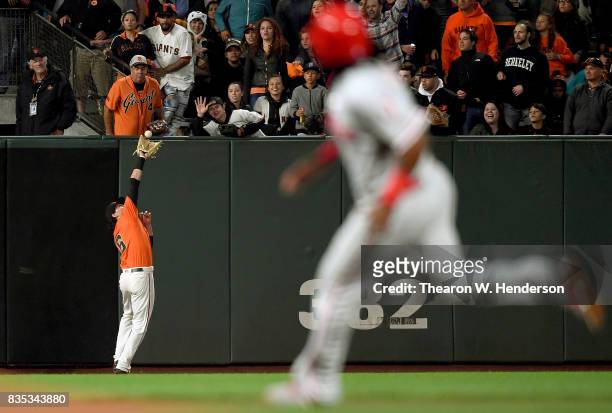 Jarrett Parker of the San Francisco Giants runs back to the wall to catch a fly ball, taking a hit away from Tommy Joseph of the Philadelphia...