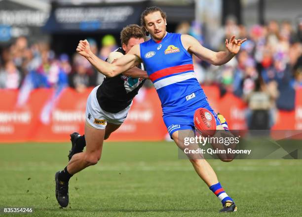 Marcus Bontempelli of the Bulldogs kicks whilst being tackled by Brad Ebert of the Power during the round 22 AFL match between the Western Bulldogs...