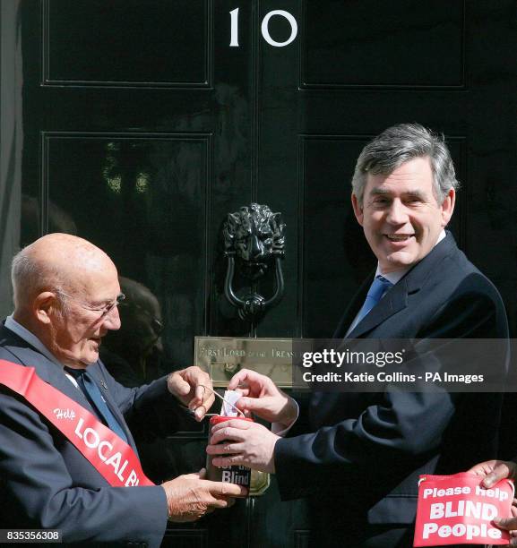 Vice President of GLFB, Sir Stirling Moss, accepts Prime Minster Gordon Brown's traditional donation to mark Geranium Day outside 10 Downing Street.