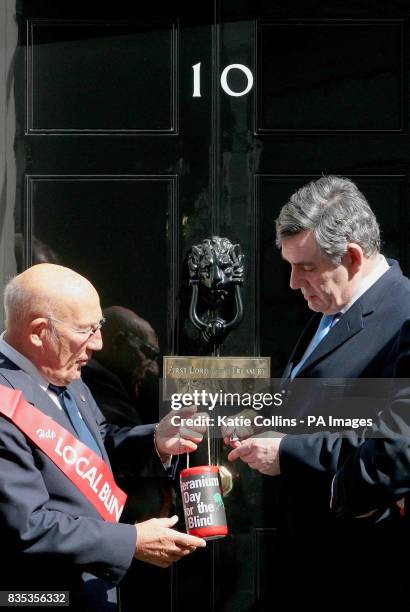 Vice President of GLFB, Sir Stirling Moss, accepts Prime Minster Gordon Brown's traditional donation to mark Geranium Day outside 10 Downing Street.