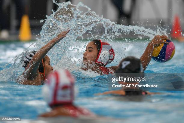 Indonesia's Hudaidah Kadir is challenged for the ball by Malaysia players during their women's water polo round match at the 29th Southeast Asian...