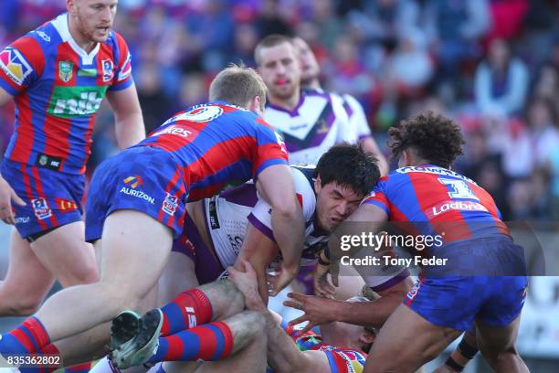 Jordan McLean of the Storm is tackled during the round 24 NRL match between the Newcastle Knights and the Melbourne Storm at McDonald Jones Stadium...