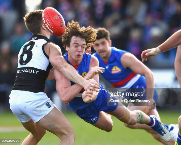 Liam Picken of the Bulldogs handballs whilst being tackled by Hamish Hartlett of the Power during the round 22 AFL match between the Western Bulldogs...