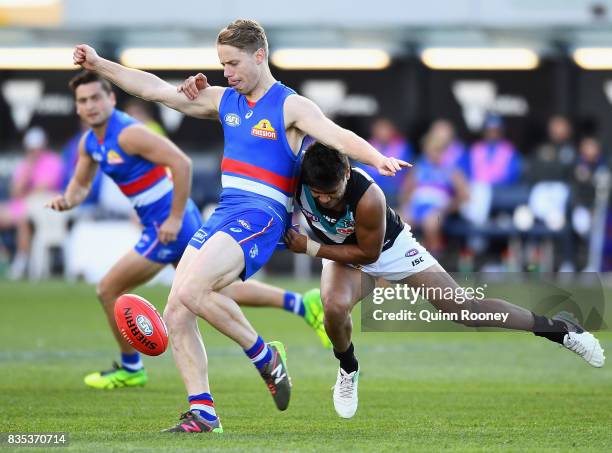 Lachie Hunter of the Bulldogs kicks whilst being tackled by Jake Neade of the Power during the round 22 AFL match between the Western Bulldogs and...