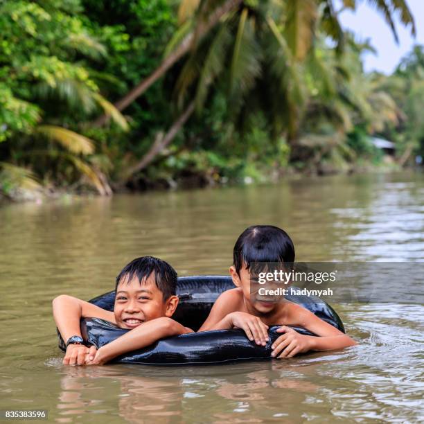 zwei kleine vietnamesische jungs baden im mekong river delta, vietnam - kinder badeboot stock-fotos und bilder