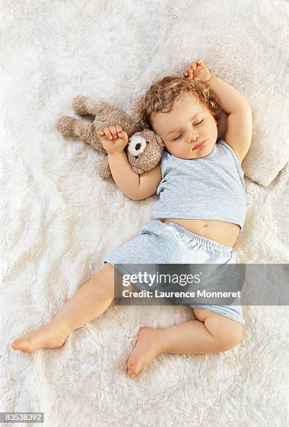 toddler sleeping arms raised up with a teddy bear - beautiful blonde babes stockfoto's en -beelden