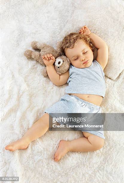 toddler sleeping arms raised up with a teddy bear - baby toy stock pictures, royalty-free photos & images